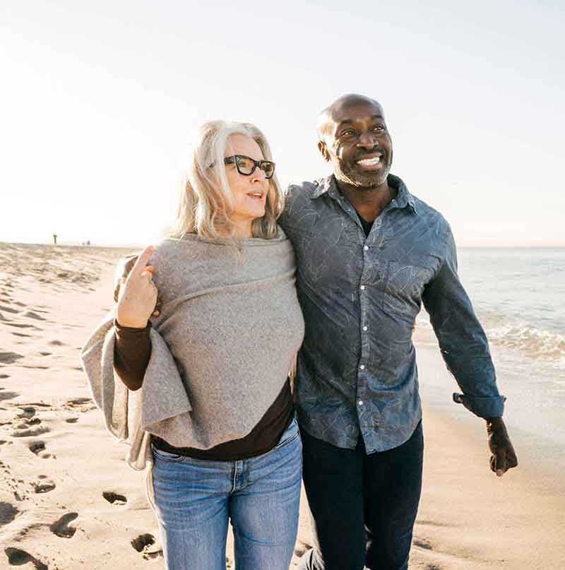 Mixed race couple walking on beach and enjoying life despite having hearing loss. 